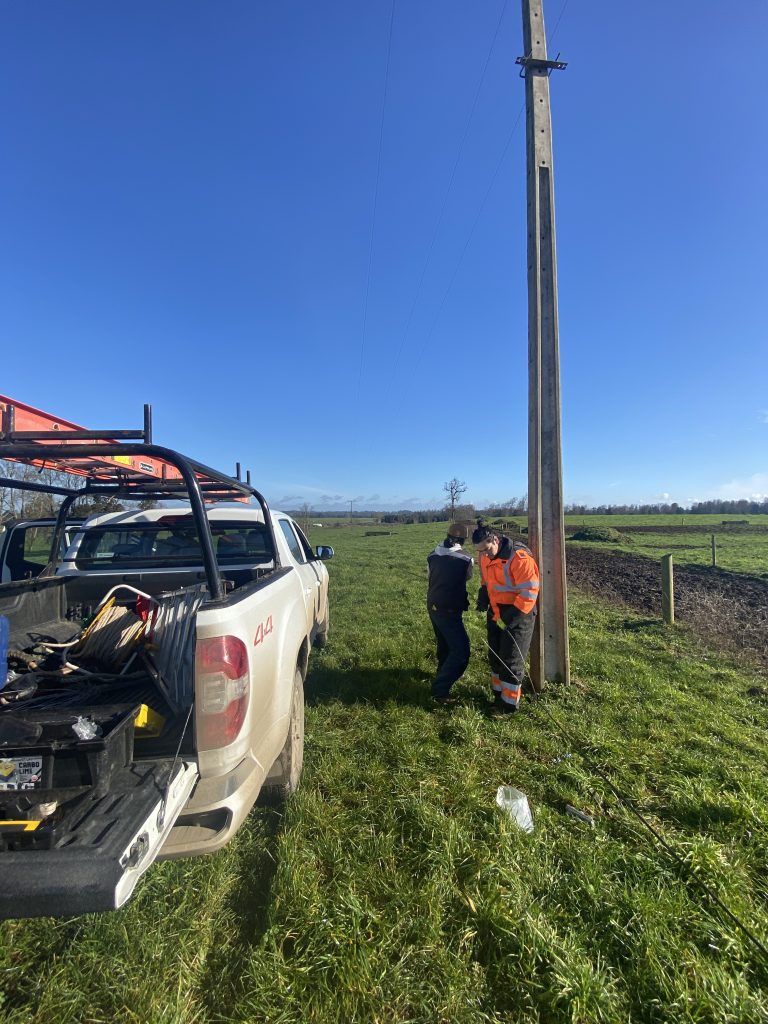 Técnicos de Agrotelecom instalando enlace inalámbrico sobre poste en praderas de Fundo Tronador, Purranque